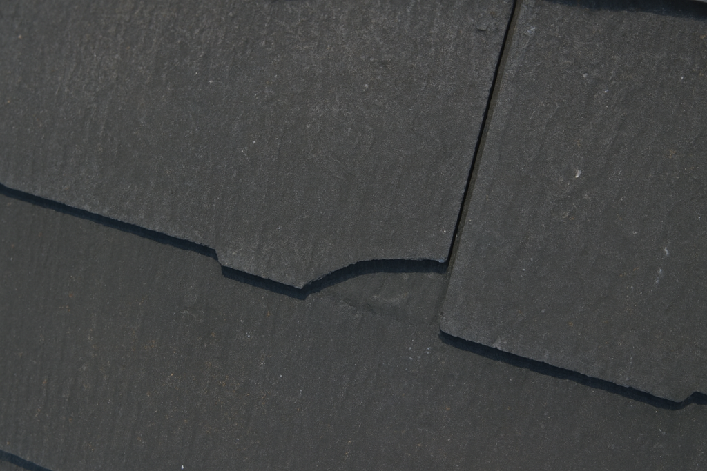 劣化したスレートが割れて破片が落下した屋根の状態