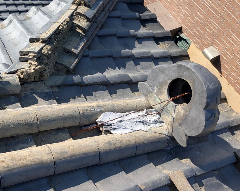 下り棟の先端部分をめくり鬼瓦固定用の銅線を引き直して復旧している施工中の様子