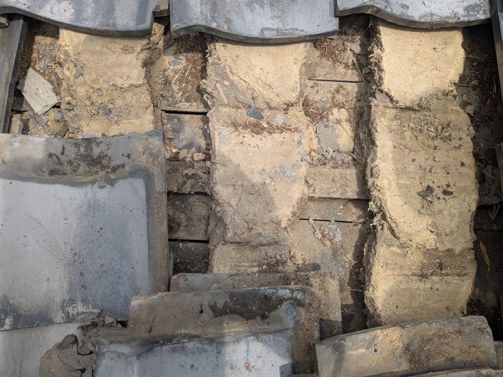 防水紙が入っていない土葺き構造のいぶし瓦屋根を点検している様子（表面側）