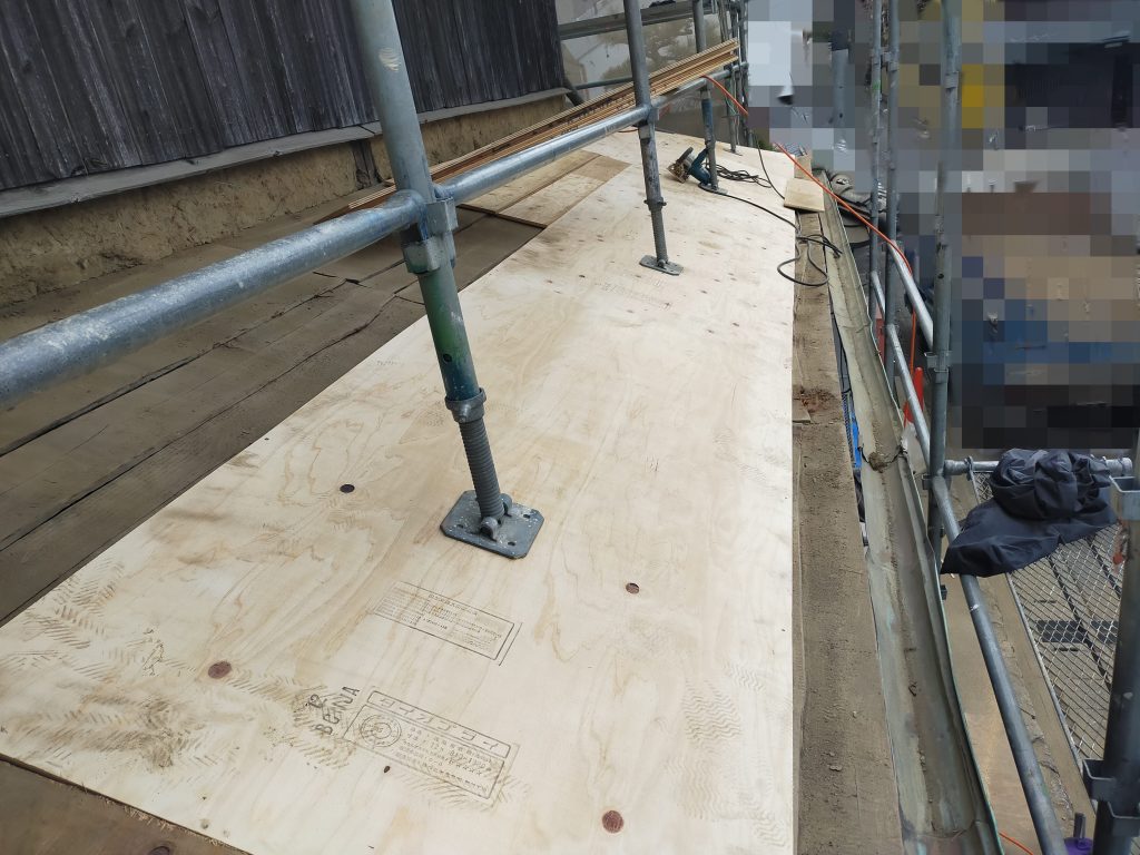 劣化状況を確認したうえで構造用合板を施工し、下屋根の下地を整えている様子